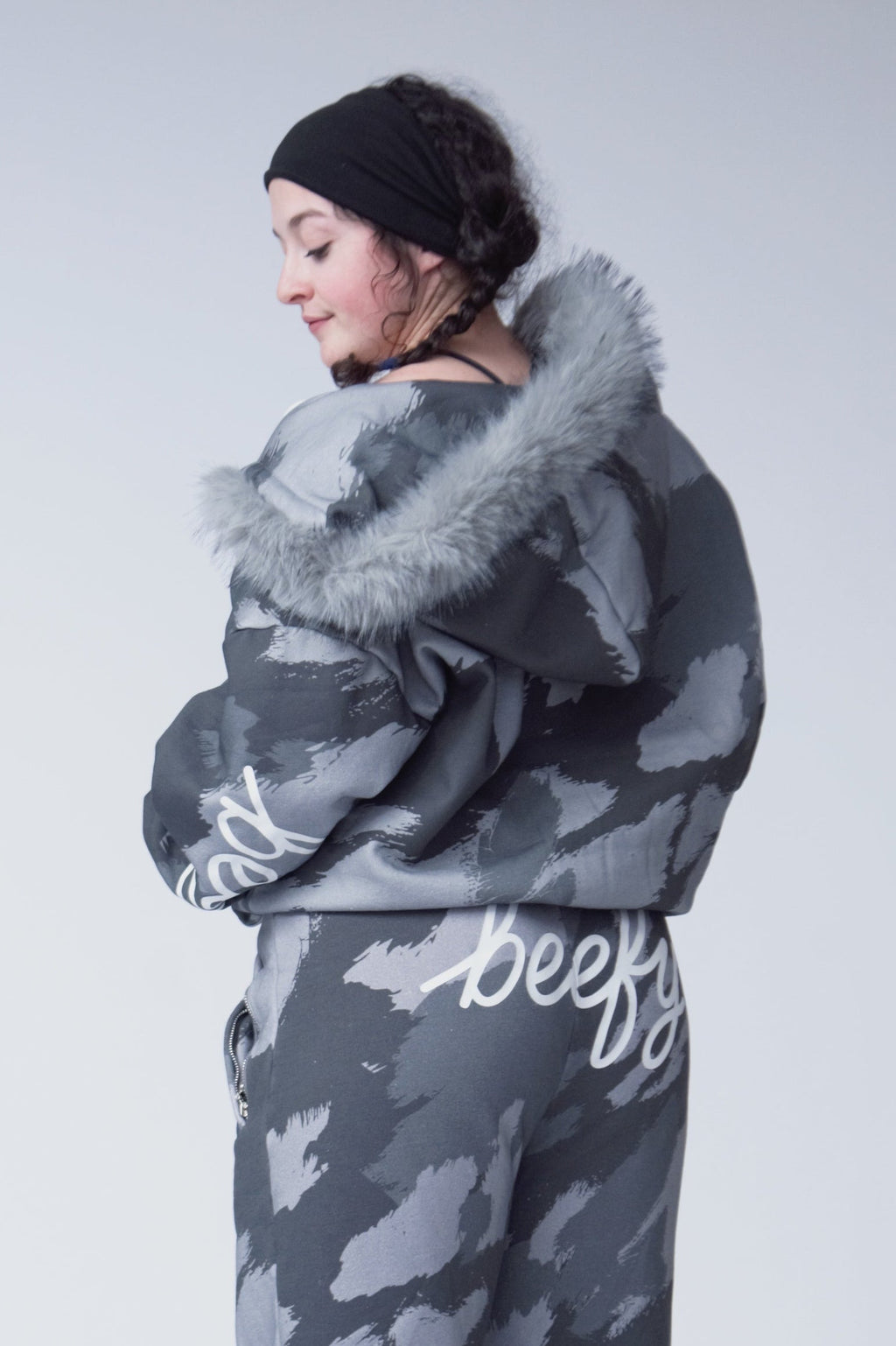 Person wearing a gray cow print outfit with a fur-lined hood against a white background