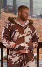 Two people outside wearing cow-print zip-up hoodies