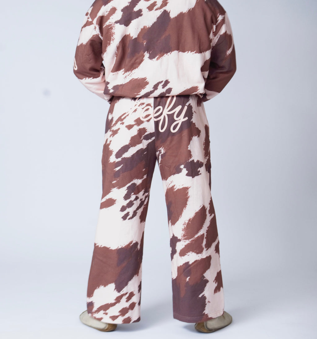 Man wearing cow-print sweatpants on a plain white background