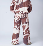 Man wearing cow-print sweatpants on a plain white background