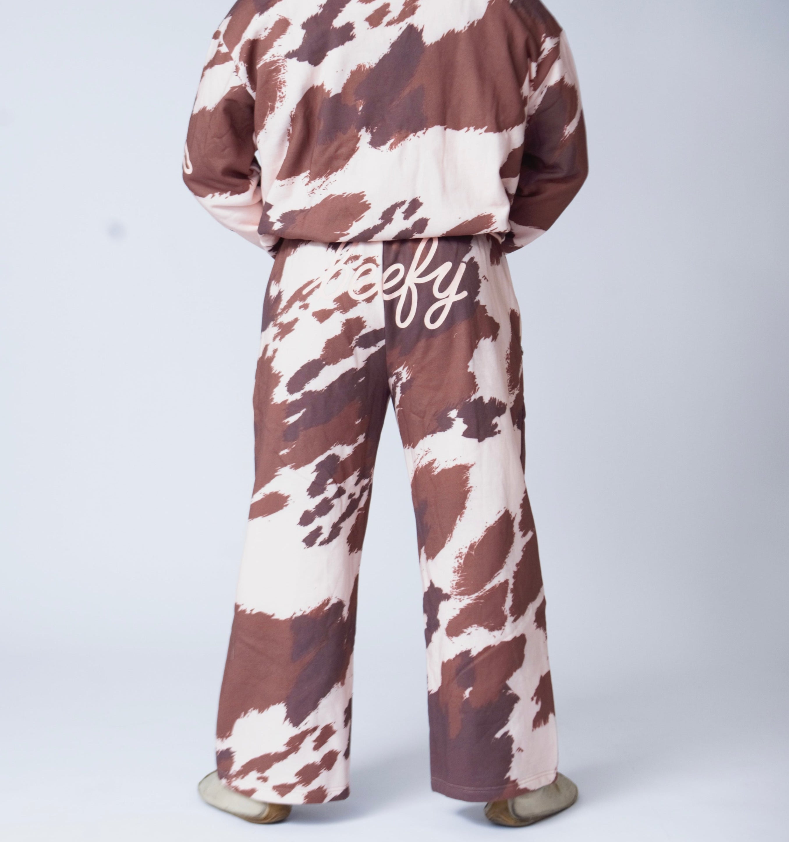 Man wearing cow-print sweatpants on a plain white background